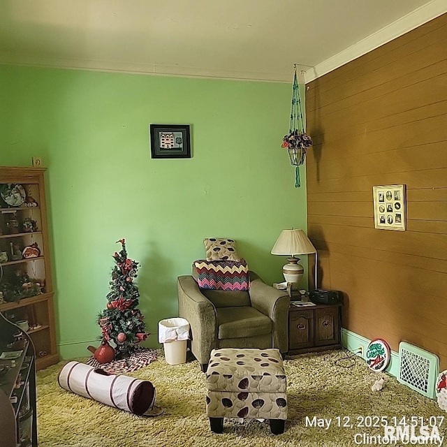 sitting room featuring crown molding, carpet floors, and wood walls