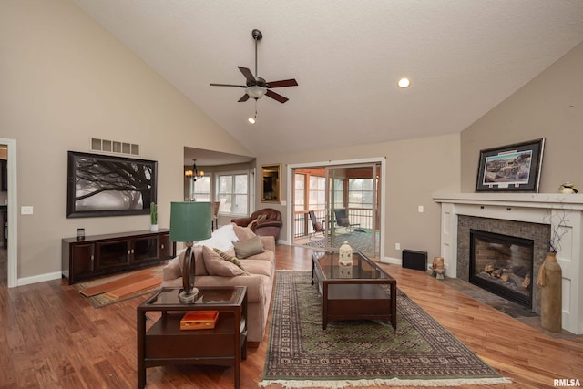 9932 123rd St, Davenport, IA 52804 - living area featuring ceiling fan, high vaulted ceiling, a tiled fireplace, wood finished floors, and baseboards