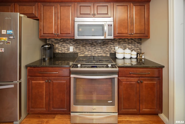 9932 123rd St, Davenport, IA 52804 - kitchen featuring stainless steel appliances, tasteful backsplash, light wood-style flooring, and dark stone counters