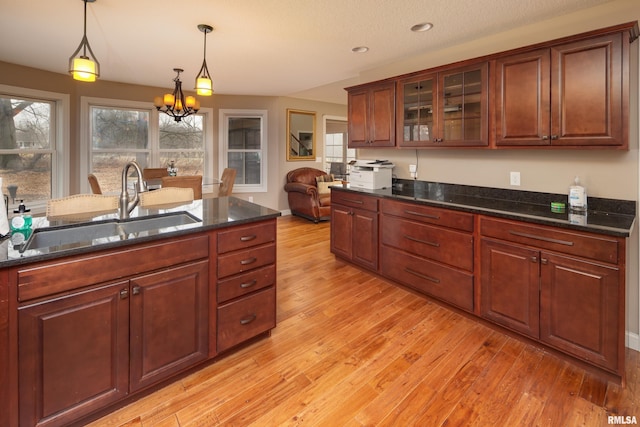 9932 123rd St, Davenport, IA 52804 - kitchen with a sink, light wood-style floors, hanging light fixtures, a chandelier, and glass insert cabinets