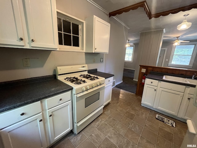 1935 12th Ave, Moline, IL 61265 - kitchen with gas range gas stove, ceiling fan, dark countertops, white cabinets, and ornamental molding