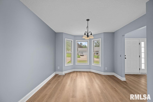 3217 Arlington Cir, Davenport, IA 52803 - unfurnished dining area with light wood finished floors, a chandelier, baseboards, and a textured ceiling