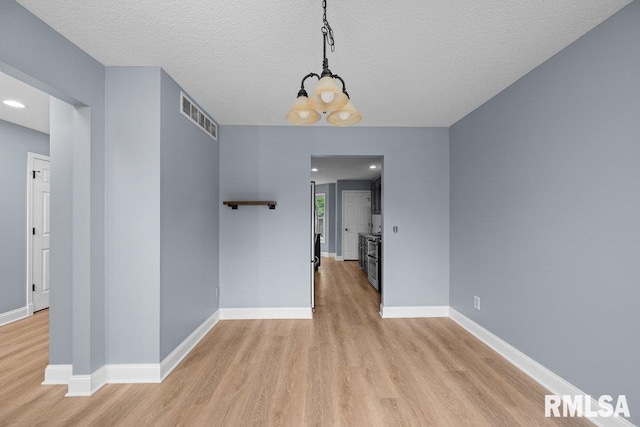 3217 Arlington Cir, Davenport, IA 52803 - spare room with light wood-type flooring, a chandelier, baseboards, and a textured ceiling