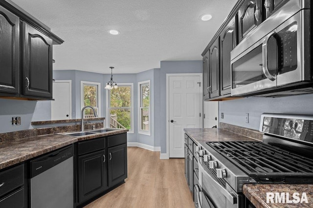 3217 Arlington Cir, Davenport, IA 52803 - kitchen featuring appliances with stainless steel finishes, a sink, dark countertops, light wood-type flooring, and a textured ceiling