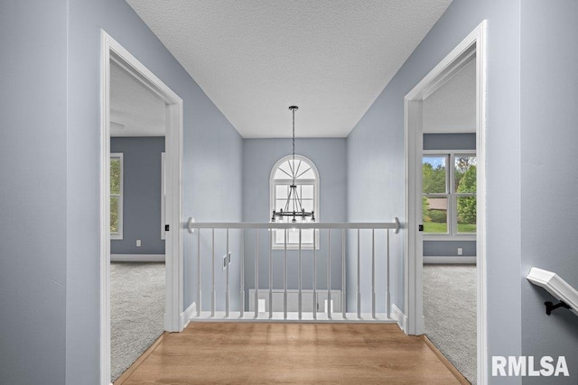 3217 Arlington Cir, Davenport, IA 52803 - hallway with carpet flooring, a chandelier, baseboards, an upstairs landing, and a textured ceiling