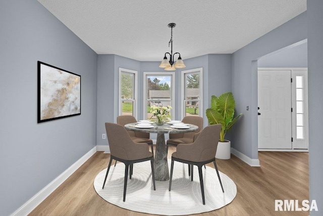 3217 Arlington Cir, Davenport, IA 52803 - dining area with a chandelier, baseboards, light wood-style floors, and a textured ceiling