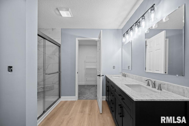 3217 Arlington Cir, Davenport, IA 52803 - bathroom with a textured ceiling, a shower stall, wood finished floors, a spacious closet, and baseboards