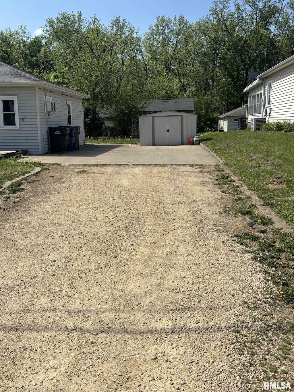 view of yard featuring a storage shed, an outdoor structure, view of scattered trees, and driveway