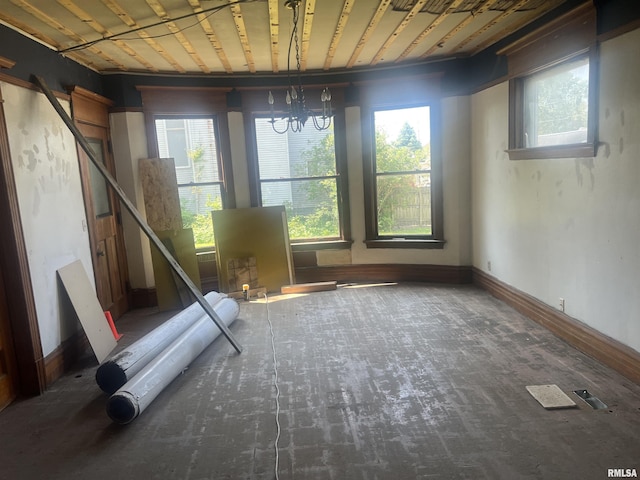 miscellaneous room with plenty of natural light, a chandelier, and baseboards