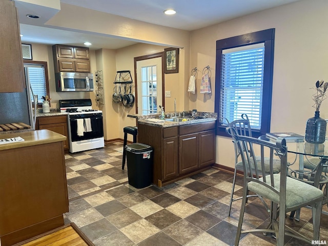 kitchen with appliances with stainless steel finishes, a sink, baseboards, and recessed lighting