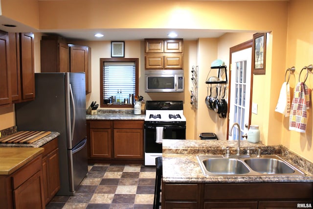 kitchen featuring appliances with stainless steel finishes, a sink, and brown cabinetry