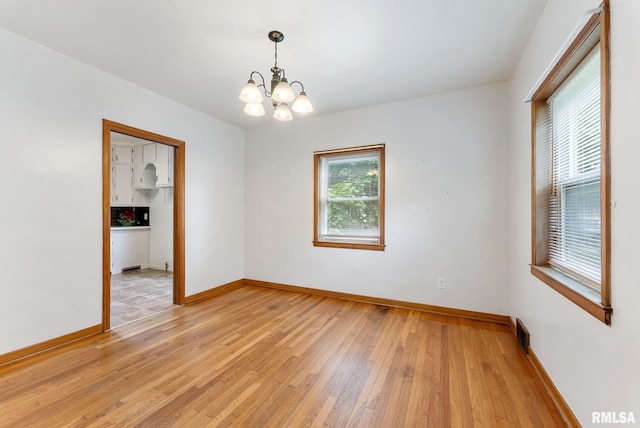 101 N Ridge St, Cambridge, IL 61238 - empty room with a chandelier, light wood-style floors, and baseboards