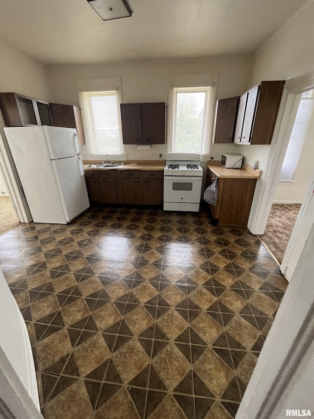 2801 Roosevelt St, Clinton, IA 52732 - kitchen featuring white appliances, dark brown cabinets, light countertops, and a sink