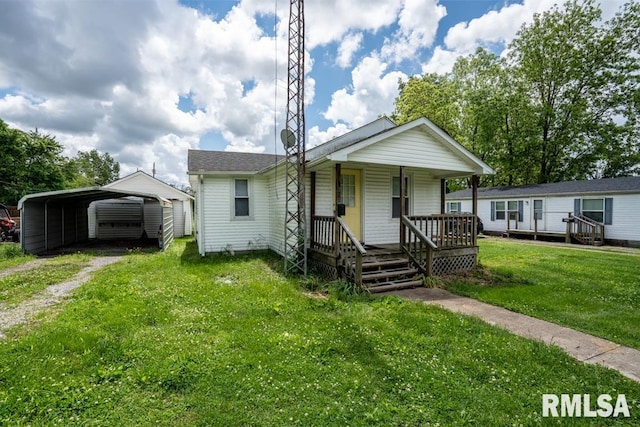 view of front facade featuring dirt driveway, a detached carport, covered porch, and a front yard