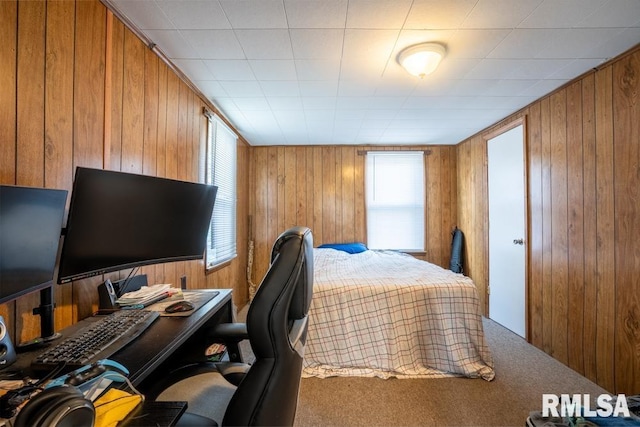 bedroom with wooden walls, carpet, and a desk