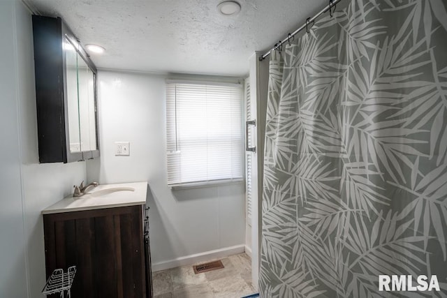 full bathroom with a textured ceiling, vanity, a shower with shower curtain, and baseboards