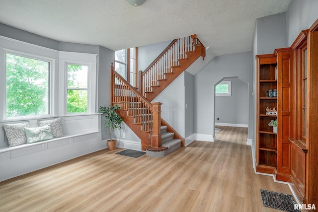 534 Lincoln Ct, Davenport, IA 52804 - staircase with wood finished floors, healthy amount of natural light, a textured ceiling, baseboards, and arched walkways