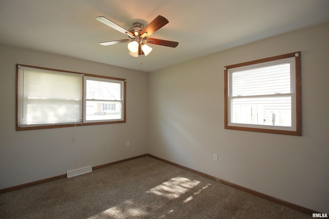 carpeted spare room with a ceiling fan and baseboards
