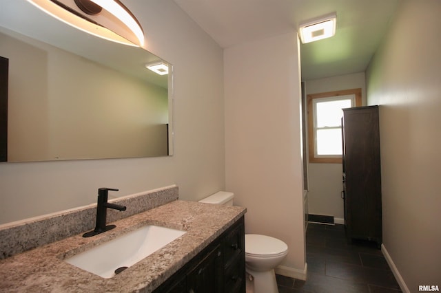 bathroom with toilet, vanity, tile patterned flooring, and baseboards