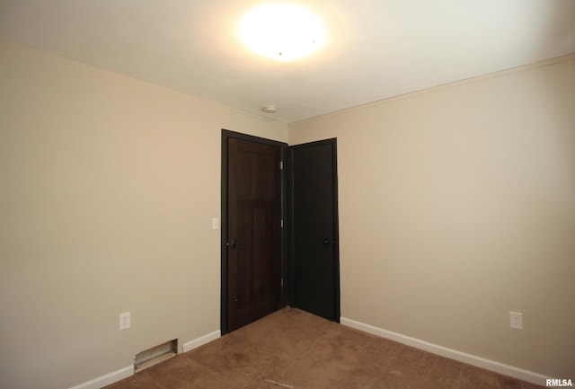 empty room featuring carpet floors, baseboards, and a smoke detector