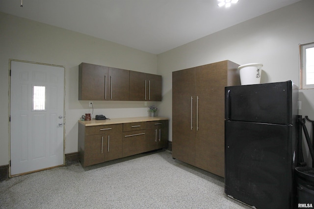kitchen with freestanding refrigerator, dark brown cabinets, and light countertops