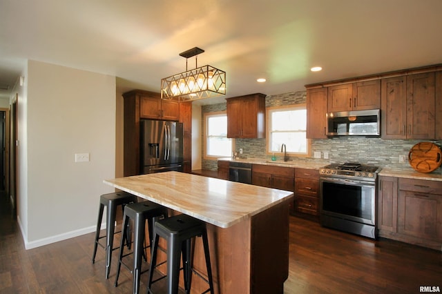 kitchen featuring stainless steel appliances, backsplash, dark wood-style floors, recessed lighting, and a kitchen breakfast bar