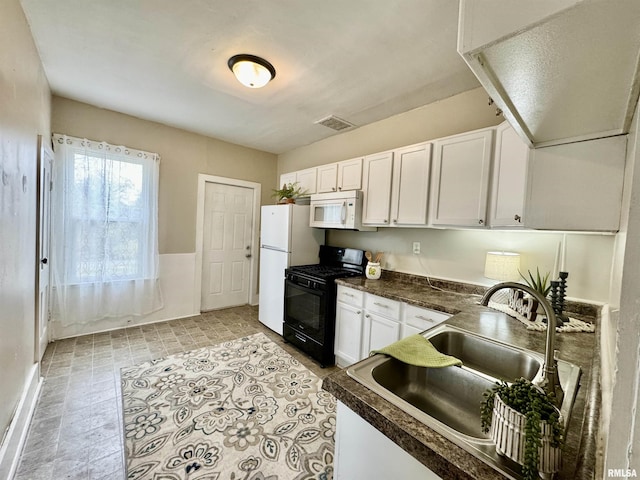 1207 Tremont Ave, Davenport, IA 52803 - kitchen featuring white appliances, dark countertops, white cabinetry, and a sink