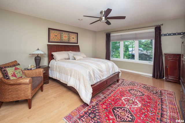 bedroom with light wood-style floors, baseboards, and a ceiling fan