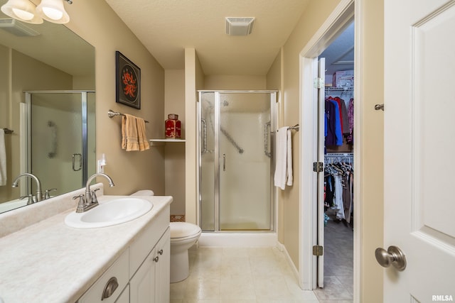 full bathroom featuring a shower stall, vanity, tile patterned flooring, a walk in closet, and toilet