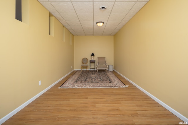 unfurnished dining area with light wood-style floors, baseboards, and a paneled ceiling