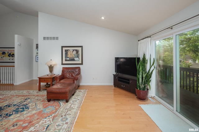 living room featuring lofted ceiling, light wood-style flooring, baseboards, and recessed lighting