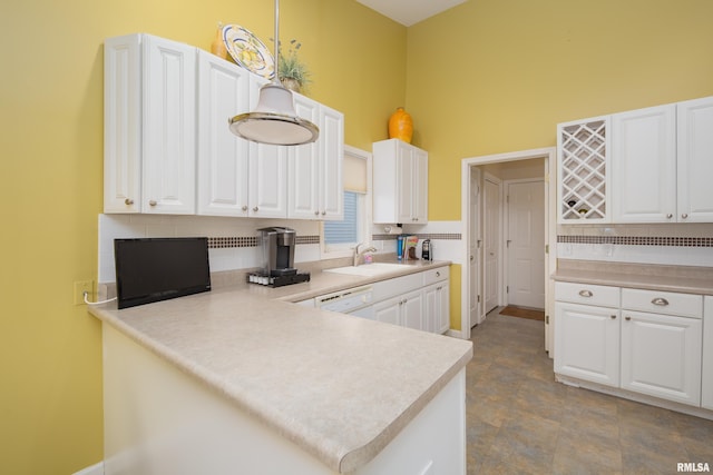 kitchen with tasteful backsplash, a towering ceiling, a sink, white cabinets, and a peninsula