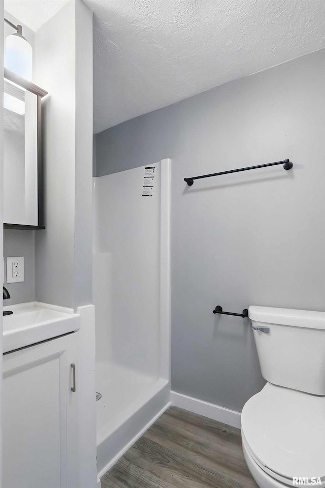 2615 Central Ave, Bettendorf, IA 52722 - bathroom featuring a shower stall, toilet, wood finished floors, baseboards, and vanity