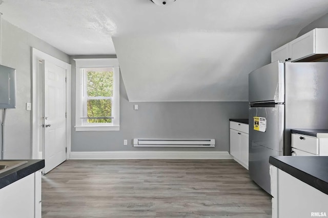 2615 Central Ave, Bettendorf, IA 52722 - kitchen featuring a baseboard radiator, freestanding refrigerator, dark countertops, white cabinetry, and vaulted ceiling