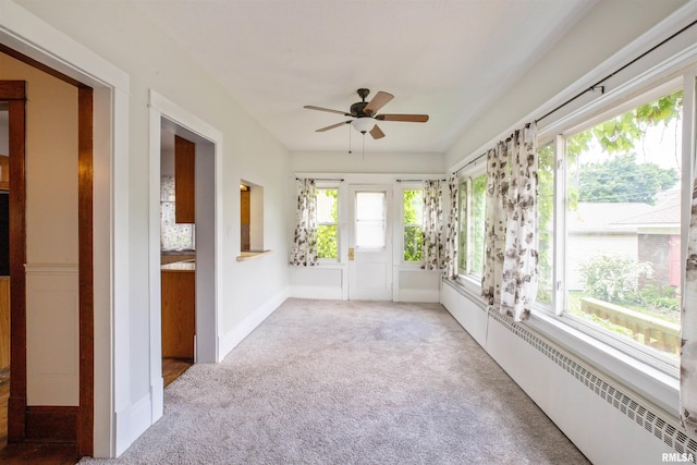 unfurnished sunroom featuring carpet flooring and a baseboard heating unit