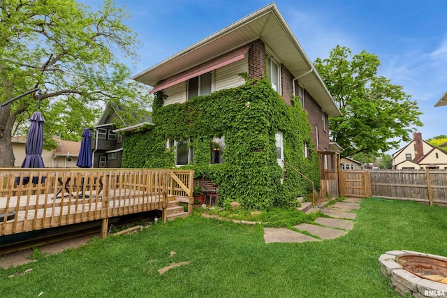 rear view of property featuring a deck and brick siding