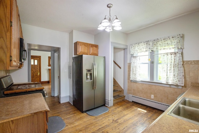 kitchen with stainless steel fridge, a baseboard heating unit, range with gas cooktop, light wood-type flooring, and black microwave