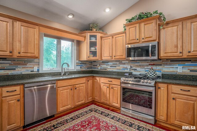 1004 Wild W Dr, Le Claire, IA 52753 - kitchen with appliances with stainless steel finishes, a sink, lofted ceiling, decorative backsplash, and glass insert cabinets