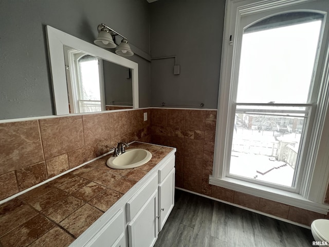 724 W 8th St, Davenport, IA 52804 - bathroom with healthy amount of natural light, vanity, wood finished floors, tile walls, and wainscoting