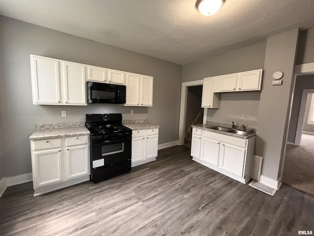 1627 W 4th St, Davenport, IA 52802 - kitchen with black appliances, a sink, baseboards, and white cabinetry