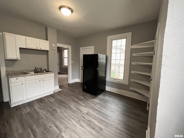 1627 W 4th St, Davenport, IA 52802 - kitchen with freestanding refrigerator, a sink, white cabinets, dark wood finished floors, and baseboards