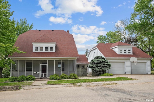 view of front facade with a sunroom, a gambrel roof, a garage, and driveway