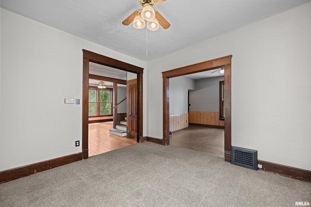 empty room with a ceiling fan, carpet, baseboards, and stairs