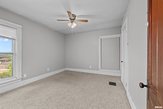 spare room with healthy amount of natural light, a ceiling fan, baseboards, and carpet flooring