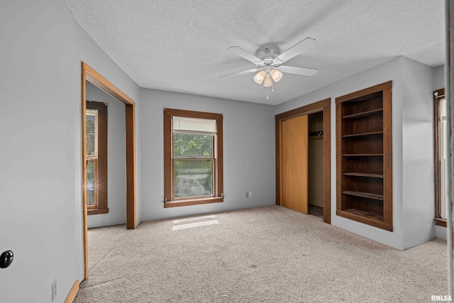 unfurnished bedroom featuring a textured ceiling, carpet flooring, and a ceiling fan