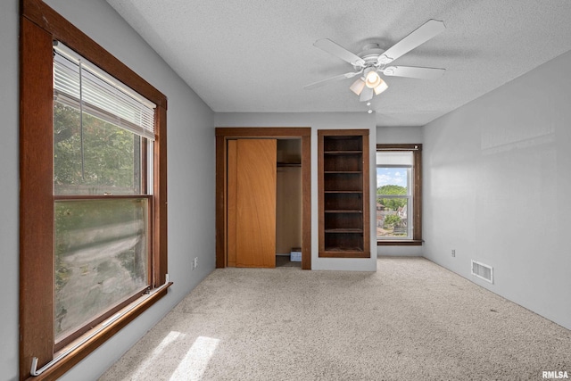 unfurnished bedroom with a textured ceiling, carpet flooring, and ceiling fan