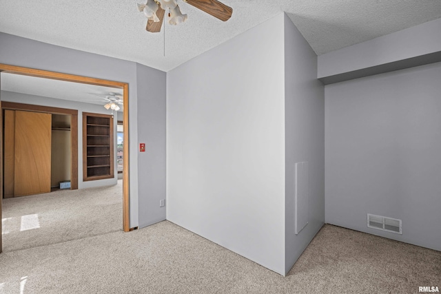 unfurnished room featuring a ceiling fan, carpet floors, and a textured ceiling