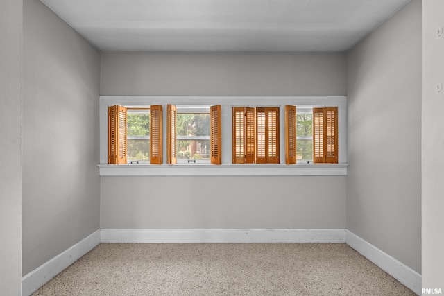 spare room featuring healthy amount of natural light, baseboards, and carpet floors