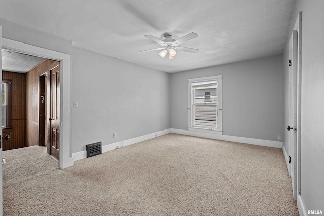 carpeted spare room with ceiling fan and baseboards