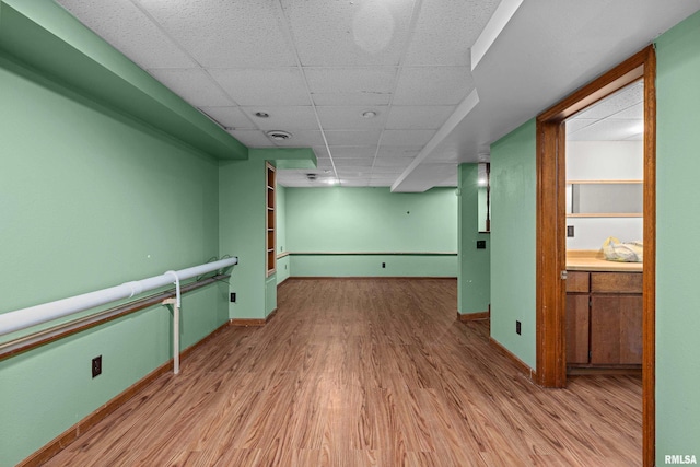 spare room with wood finished floors, a paneled ceiling, and baseboards